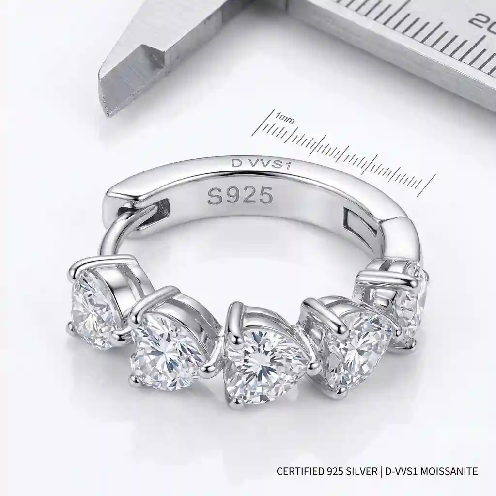 Ultra-detailed macro close-up of the metal and stone specifications of the heart moissanite earrings. The image clearly shows the S925 sterling silver stamp on the earring post or butterfly back, indicating genuine 925 silver. The rhodium plating is visibly flawless — mirror-polished, bright white, and luxurious. The prong setting is perfectly crafted, securely holding the heart-shaped D-color VVS1 moissanite. A small ruler or caliper is softly visible at the edge to indicate dimensions. The background is a clean pure white surface. High-key studio lighting accentuates the pristine metal quality. The composition is technical, precise, and transparent — a visual quality certificate. Professional jewelry catalog photography. True material rendering. 8K ultra HD.