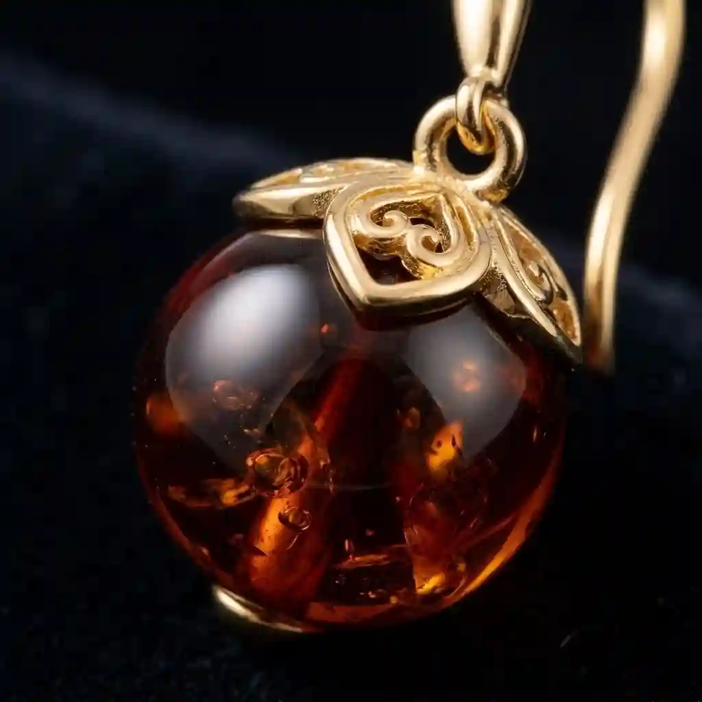 blood amber earrings close-up — natural amber pendant showing translucent crimson resin with vintage filigree detail