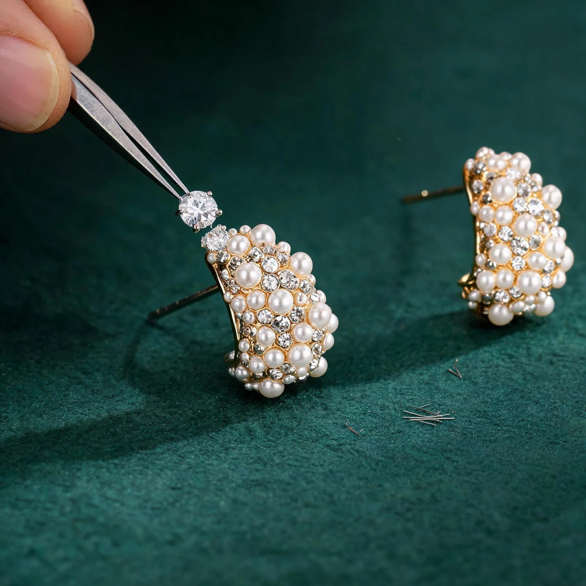 Jeweler setting cubic zirconia into a gold pearl flower earring