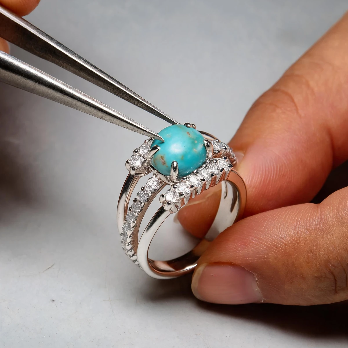 Jeweler setting natural turquoise into an 18K gold plated silver ring