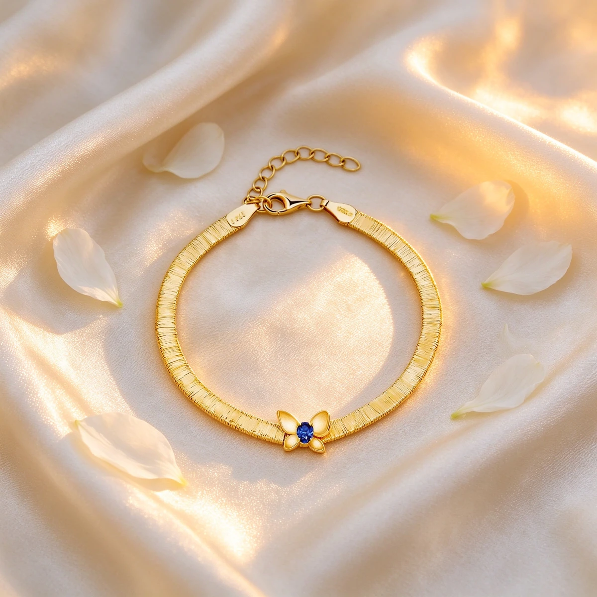 Gold butterfly bracelet on cream silk satin with petals