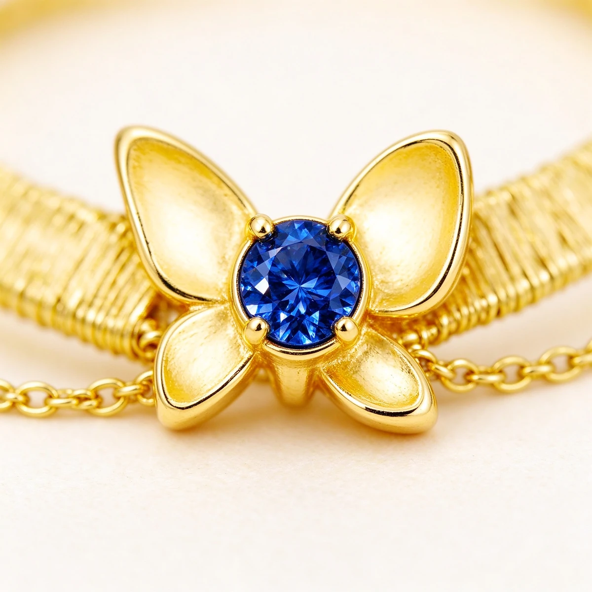 Round blue stone detail on gold butterfly bracelet