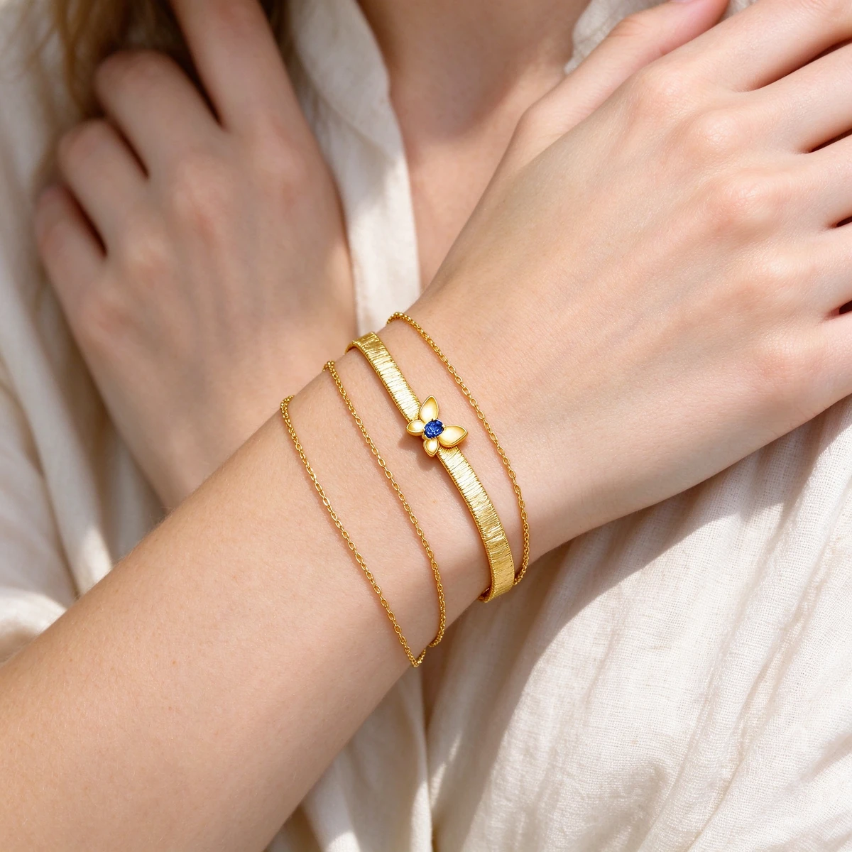 Layered gold chain bracelets on Western woman wrist - butterfly bracelet
