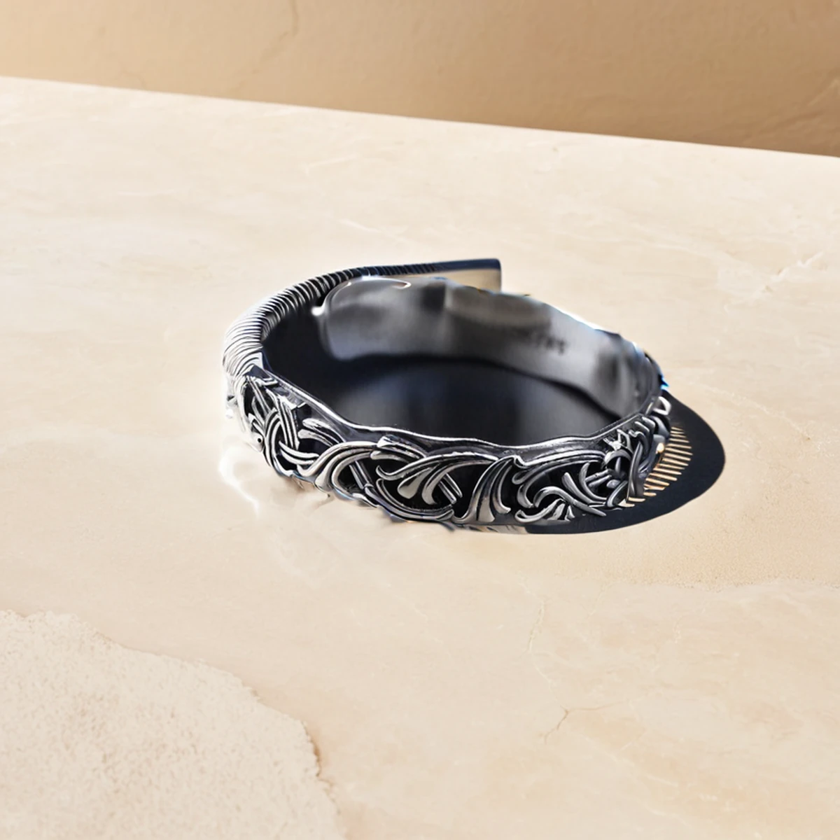 Oxidized silver cuff bracelet on travertine stone in a luxury editorial scene
