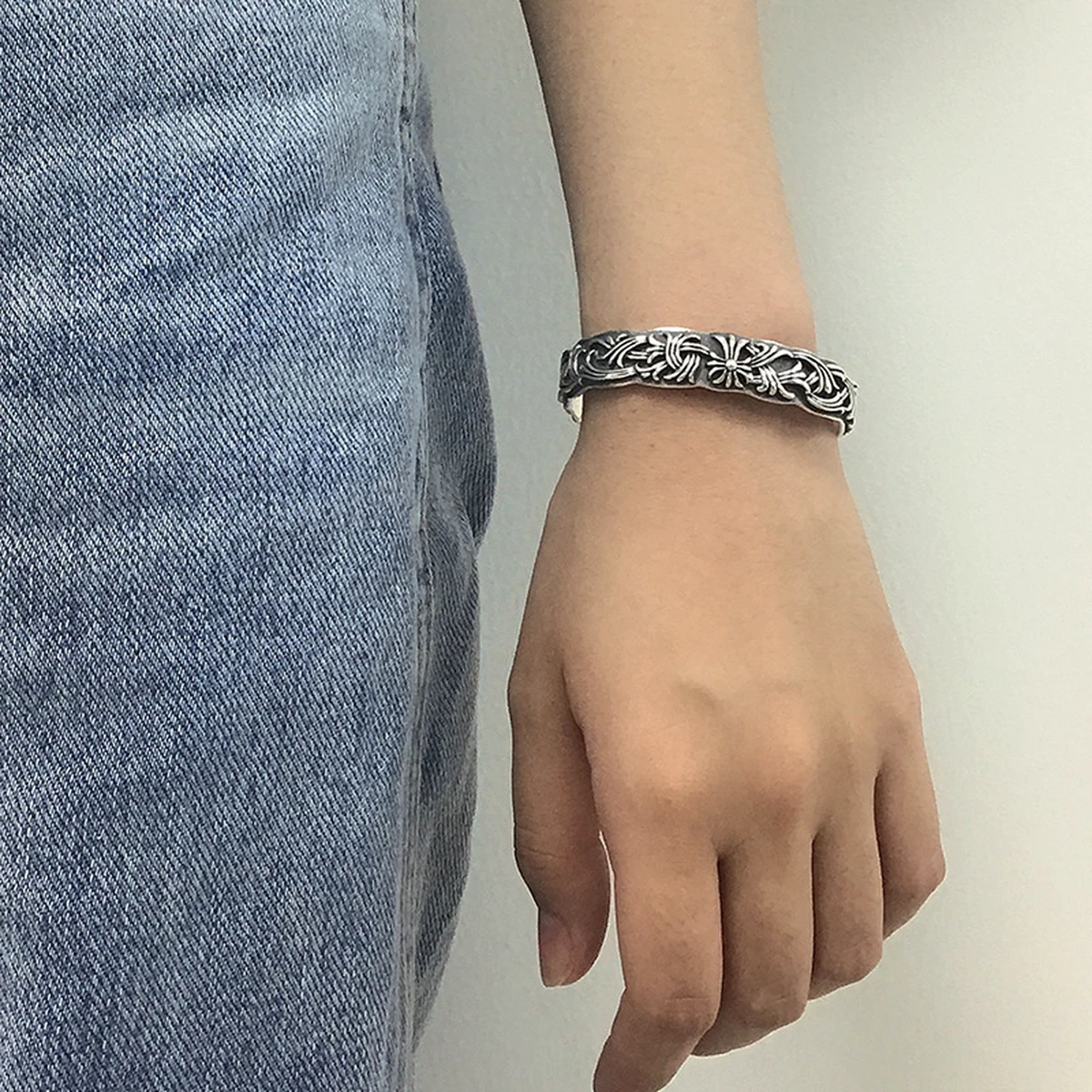Woman wearing the carved silver cuff bracelet on a denim outfit