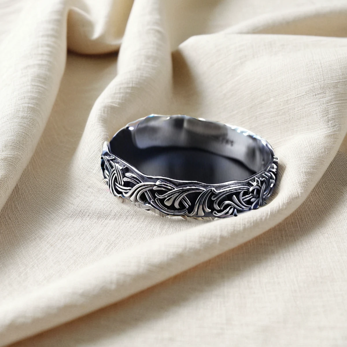 Oxidized silver cuff bracelet styled on beige linen with a delicate silver chain