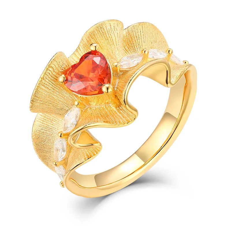 Cubic zirconia ring with gold ruffle heart design on white background