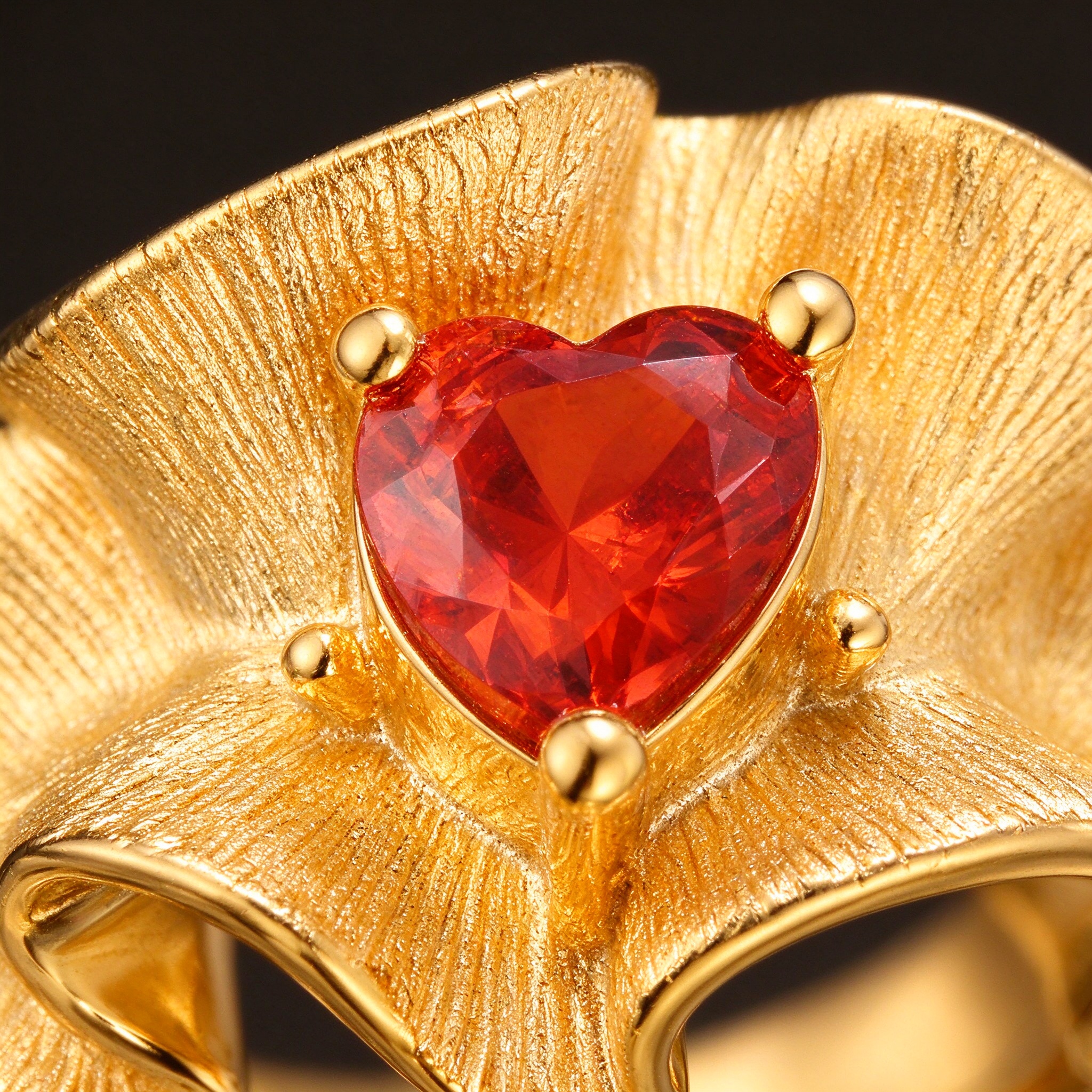 Close-up of brushed gold ruffle texture and four-bead heart red CZ setting