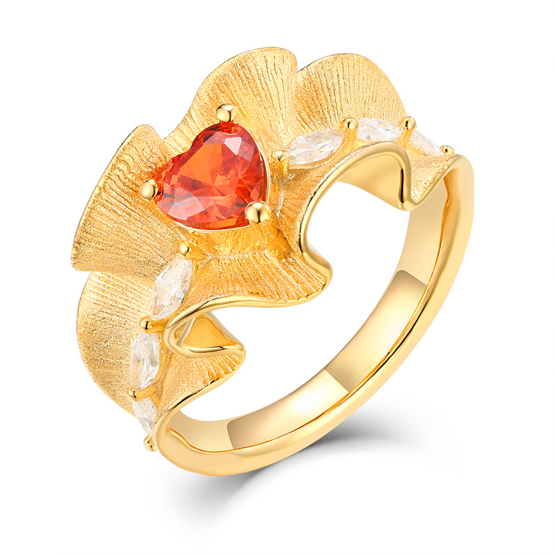 Gold ruffle wide-band statement ring with heart-shaped red cubic zirconia on white background